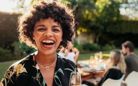 Woman smiling outdoors at a meal with friends after good bone growth and healing procedure