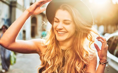 Woman in a hat smiling walking down the street