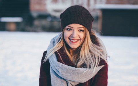 Woman Smiling with a warm coat and a hat outside in the winter