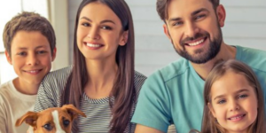 boy with dog, mom, dad, and daughter sitting together smiling